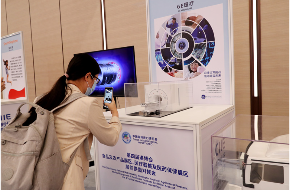 第四屆進博會食品及農產品展區、醫療器械及醫藥保健展區展前供需對接會的參會嘉賓用手機拍攝參展企業的展品模型